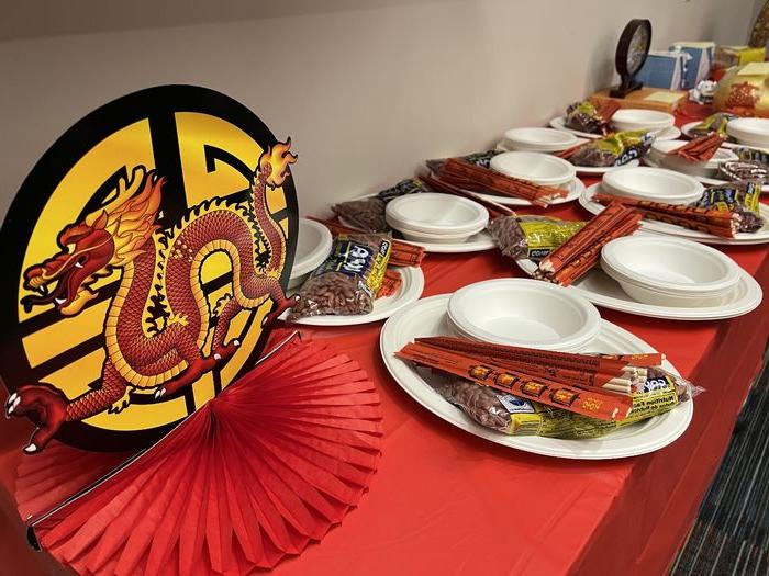 为农历新年装饰的桌子，包括纸龙, 盘子, 筷子和红色桌布.