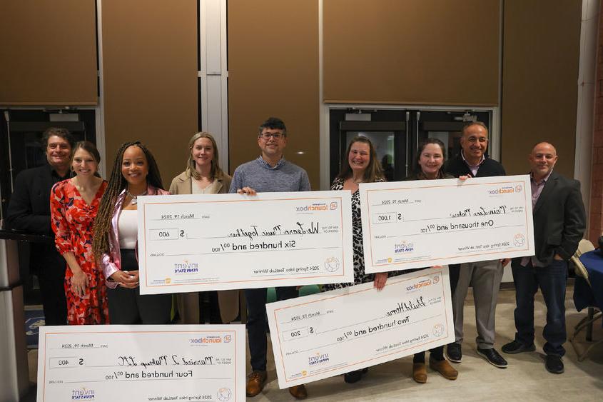 group of people holding large checks